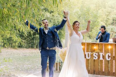 Chambre lumineuse avec lit double, commode en bois, portant à vêtements, télévision et poutre apparente au plafond.