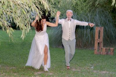 Chambre lumineuse avec lit double, commode en bois, portant à vêtements, télévision et poutre apparente au plafond.