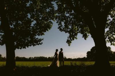 Chambre lumineuse avec lit double, commode en bois, portant à vêtements, télévision et poutre apparente au plafond.