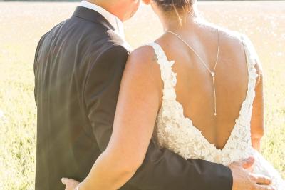 Chambre lumineuse avec lit double, commode en bois, portant à vêtements, télévision et poutre apparente au plafond.