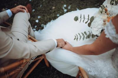 Chambre lumineuse avec lit double, commode en bois, portant à vêtements, télévision et poutre apparente au plafond.