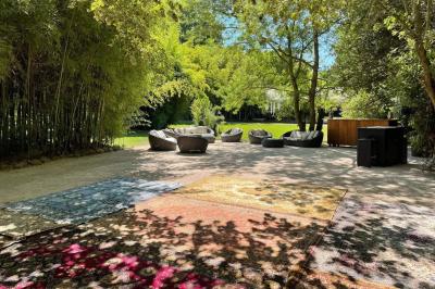 Chambre lumineuse avec lit double, commode en bois, portant à vêtements, télévision et poutre apparente au plafond.