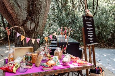 Chambre lumineuse avec lit double, commode en bois, portant à vêtements, télévision et poutre apparente au plafond.