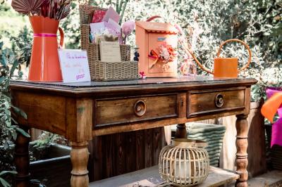 Chambre lumineuse avec lit double, commode en bois, portant à vêtements, télévision et poutre apparente au plafond.