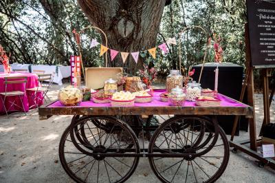 Chambre lumineuse avec lit double, commode en bois, portant à vêtements, télévision et poutre apparente au plafond.