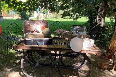 Chambre lumineuse avec lit double, commode en bois, portant à vêtements, télévision et poutre apparente au plafond.