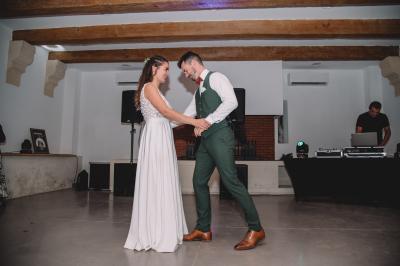 Chambre lumineuse avec lit double, commode en bois, portant à vêtements, télévision et poutre apparente au plafond.