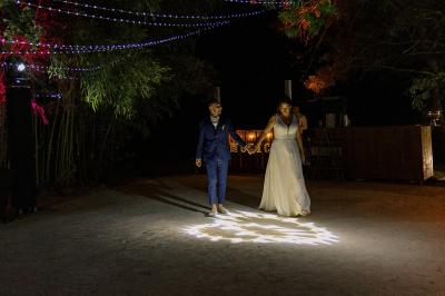 Chambre lumineuse avec lit double, commode en bois, portant à vêtements, télévision et poutre apparente au plafond.