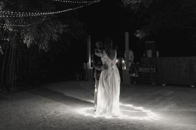 Chambre lumineuse avec lit double, commode en bois, portant à vêtements, télévision et poutre apparente au plafond.