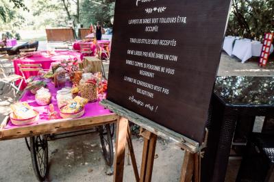 Chambre lumineuse avec lit double, commode en bois, portant à vêtements, télévision et poutre apparente au plafond.