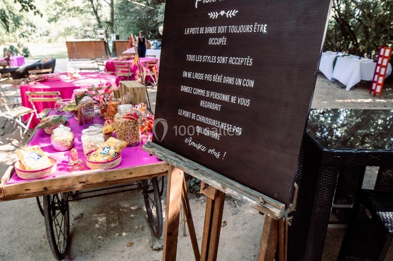 Panneau en bois affichant les règles d'une piste de danse, entouré de tables décorées pour un événement en plein air.