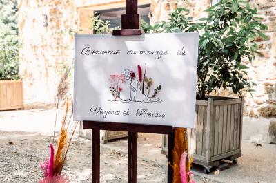 Chambre lumineuse avec lit double, commode en bois, portant à vêtements, télévision et poutre apparente au plafond.