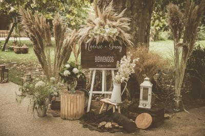 Chambre lumineuse avec lit double, commode en bois, portant à vêtements, télévision et poutre apparente au plafond.