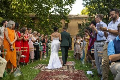 Chambre lumineuse avec lit double, commode en bois, portant à vêtements, télévision et poutre apparente au plafond.