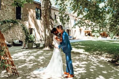 Chambre lumineuse avec lit double, commode en bois, portant à vêtements, télévision et poutre apparente au plafond.