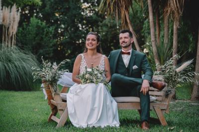 Chambre lumineuse avec lit double, commode en bois, portant à vêtements, télévision et poutre apparente au plafond.