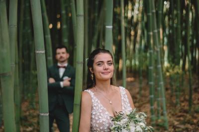 Chambre lumineuse avec lit double, commode en bois, portant à vêtements, télévision et poutre apparente au plafond.