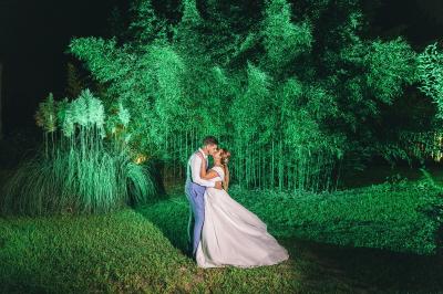 Chambre lumineuse avec lit double, commode en bois, portant à vêtements, télévision et poutre apparente au plafond.