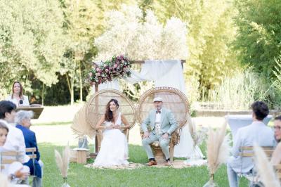 Chambre lumineuse avec lit double, commode en bois, portant à vêtements, télévision et poutre apparente au plafond.