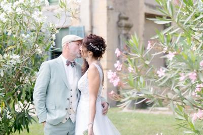Chambre lumineuse avec lit double, commode en bois, portant à vêtements, télévision et poutre apparente au plafond.