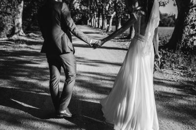 Chambre lumineuse avec lit double, commode en bois, portant à vêtements, télévision et poutre apparente au plafond.