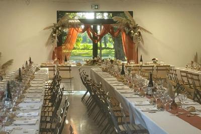 Chambre lumineuse avec lit double, commode en bois, portant à vêtements, télévision et poutre apparente au plafond.