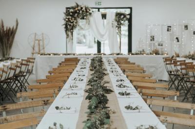 Chambre lumineuse avec lit double, commode en bois, portant à vêtements, télévision et poutre apparente au plafond.
