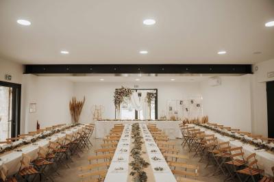 Chambre lumineuse avec lit double, commode en bois, portant à vêtements, télévision et poutre apparente au plafond.