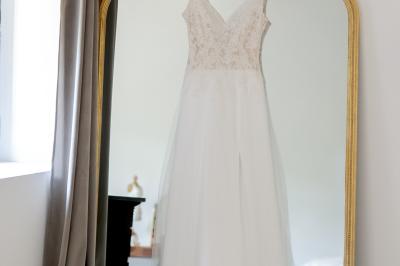 Chambre lumineuse avec lit double, commode en bois, portant à vêtements, télévision et poutre apparente au plafond.