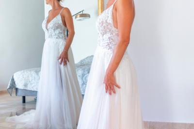 Chambre lumineuse avec lit double, commode en bois, portant à vêtements, télévision et poutre apparente au plafond.