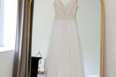 Chambre lumineuse avec lit double, commode en bois, portant à vêtements, télévision et poutre apparente au plafond.