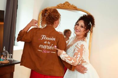 Chambre lumineuse avec lit double, commode en bois, portant à vêtements, télévision et poutre apparente au plafond.