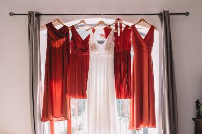 Chambre lumineuse avec lit double, commode en bois, portant à vêtements, télévision et poutre apparente au plafond.