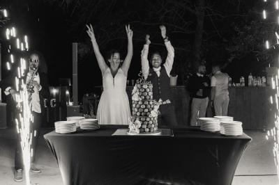 Chambre lumineuse avec lit double, commode en bois, portant à vêtements, télévision et poutre apparente au plafond.