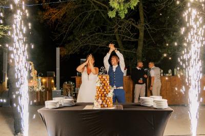 Chambre lumineuse avec lit double, commode en bois, portant à vêtements, télévision et poutre apparente au plafond.