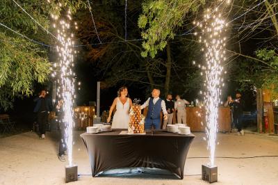 Chambre lumineuse avec lit double, commode en bois, portant à vêtements, télévision et poutre apparente au plafond.