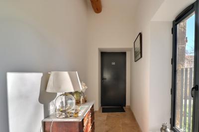 Chambre lumineuse avec lit double, commode en bois, portant à vêtements, télévision et poutre apparente au plafond.