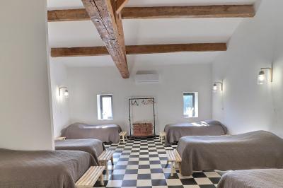 Chambre lumineuse avec lit double, commode en bois, portant à vêtements, télévision et poutre apparente au plafond.