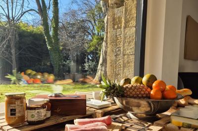 Chambre lumineuse avec lit double, commode en bois, portant à vêtements, télévision et poutre apparente au plafond.