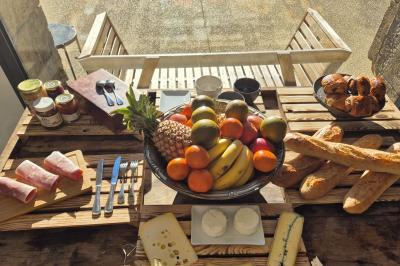 Chambre lumineuse avec lit double, commode en bois, portant à vêtements, télévision et poutre apparente au plafond.