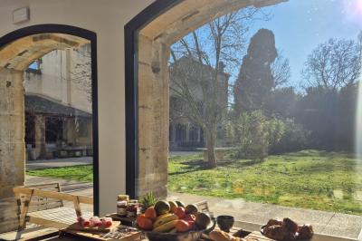 Chambre lumineuse avec lit double, commode en bois, portant à vêtements, télévision et poutre apparente au plafond.