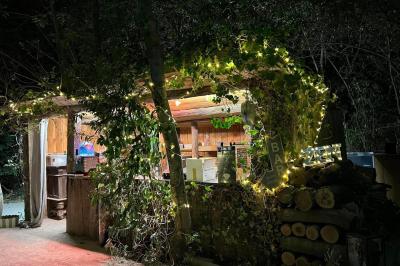 Chambre lumineuse avec lit double, commode en bois, portant à vêtements, télévision et poutre apparente au plafond.