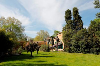 Tables rondes dressées avec nappes blanches et chaises en bois, disposées en extérieur sous des arbres verdoyants.