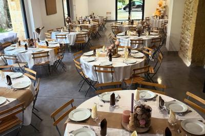 Tables rondes dressées avec nappes blanches et chaises en bois, disposées en extérieur sous des arbres verdoyants.
