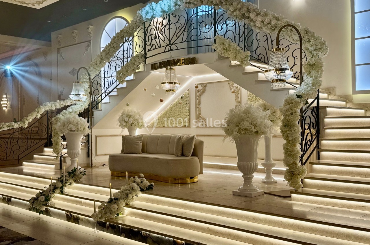 Escalier décoré de fleurs blanches avec un canapé au centre, éclairage chaleureux et ambiance élégante.