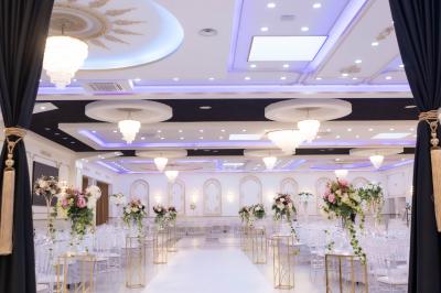 Deux fauteuils dorés ornés de motifs, entourés de fleurs blanches et roses, devant un rideau beige.