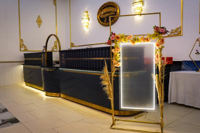 Deux fauteuils dorés ornés de motifs, entourés de fleurs blanches et roses, devant un rideau beige.