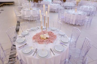 Deux fauteuils dorés ornés de motifs, entourés de fleurs blanches et roses, devant un rideau beige.