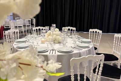 Deux fauteuils dorés ornés de motifs, entourés de fleurs blanches et roses, devant un rideau beige.