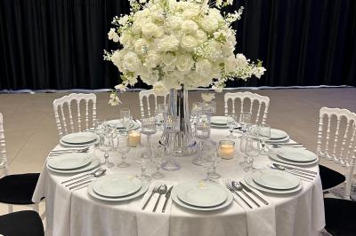 Deux fauteuils dorés ornés de motifs, entourés de fleurs blanches et roses, devant un rideau beige.